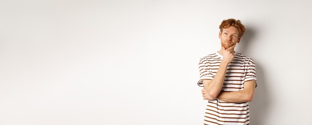 portrait of thoughtful man with red hair thinking looking at upper left corner and making choice sta