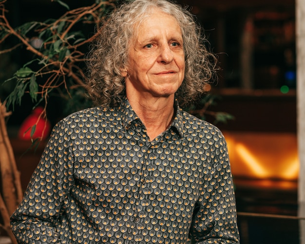 Portrait of thoughtful senior man in t-shirt 65 years old, gray curly hair, looks sadly away, actor.