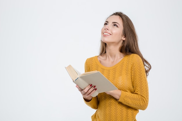 Portrait of a thoughtful woman holding book and looking up at copyspace isolated on a white background