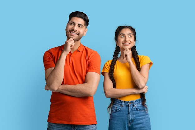 Portrait of thoughtful young arab man and woman standing on blue background