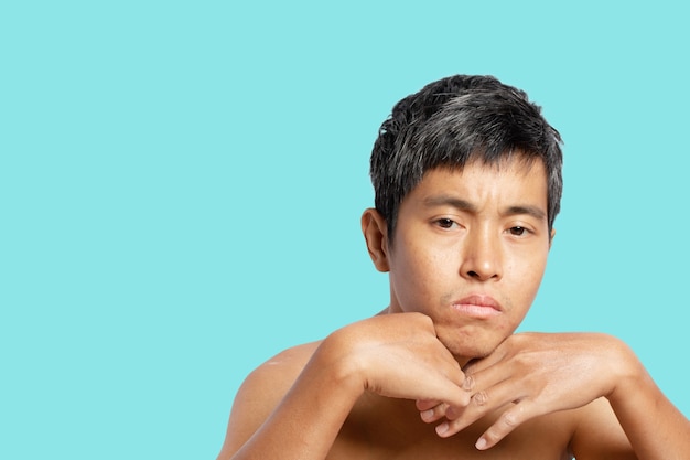 Portrait of a thoughtful young man something, a man takes off\
his shirt. isolated on blue background. clipping path.