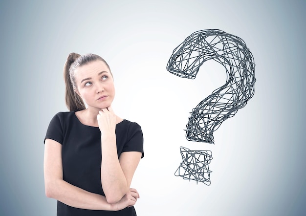 Portrait of a thoughtful young woman wearing a black T shirt and a ponytail. A large question mark is to the right