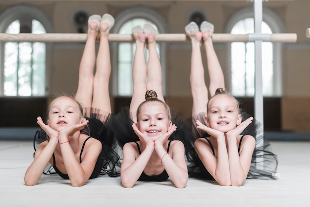 Photo portrait of three ballerina girls poising in front of barre