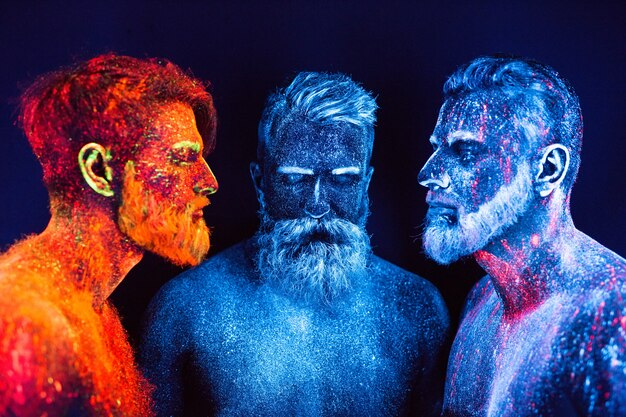 Портрет трех бородатых мужчин, окрашенных в флуоресцентные порошки.
