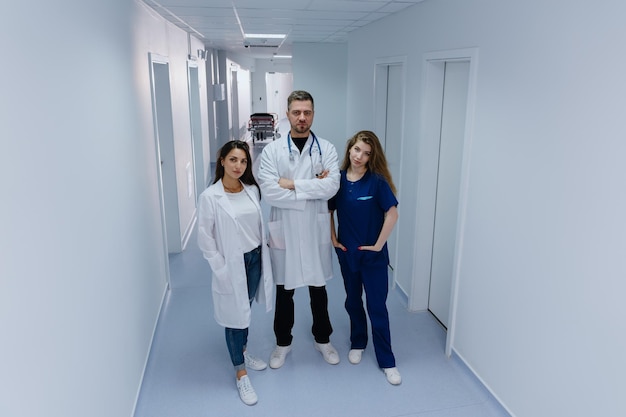 Portrait of three doctors on the background of the clinic corridor The chief doctor is a man with his colleagues