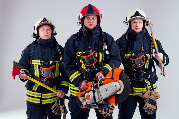 Portrait of three firefighters standing together white background studio