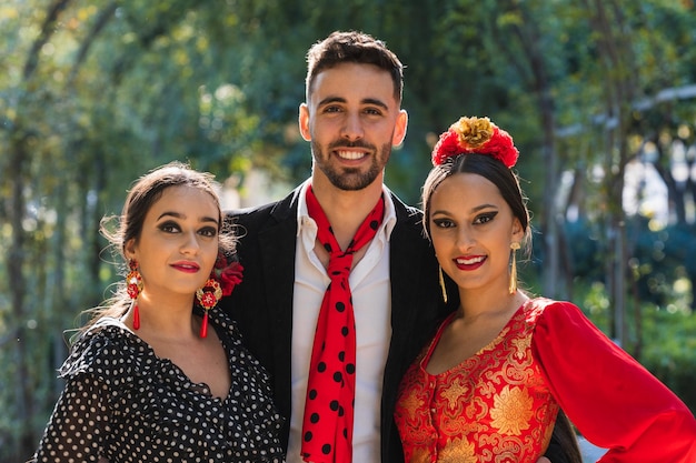 Portrait of three flamenco dancers facing the camera while smiling in a park in a sunny day