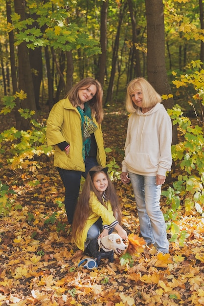 Portrait of three generations of happy beautiful women and dog looking at camera hugging and smiling