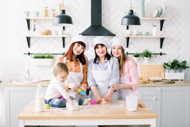 Un ritratto di tre generazioni di donne che cuociono i bigné nella cucina. la famiglia felice ama insieme l'armonia della cucina natalizia e il concetto di festa della mamma