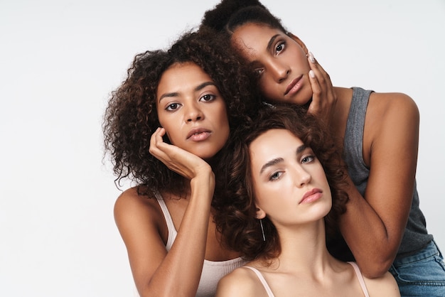 Portrait of three gorgeous multiethnic women standing together and looking at camera 