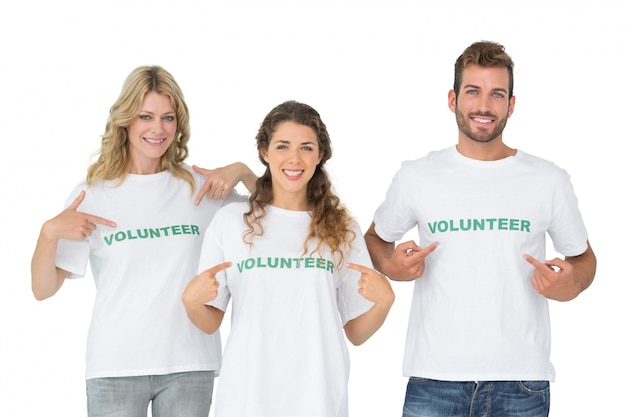 Portrait of three happy volunteers pointing to themselves