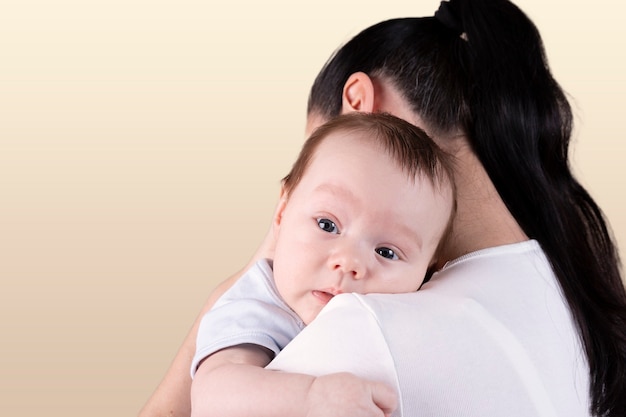 Portrait of a three-month-old baby, boy over mom's shoulder.