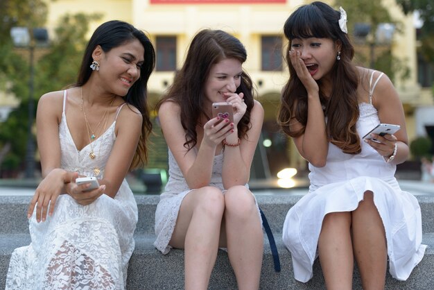 Portrait of three multi ethnic young beautiful women as friends together at the park outdoors