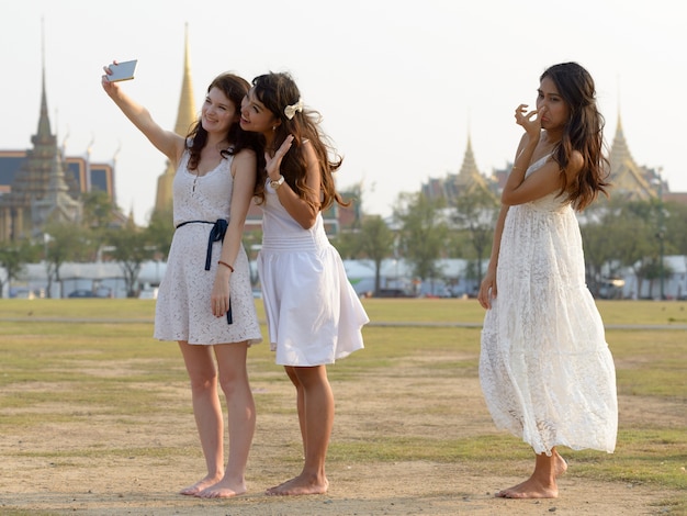 Portrait of three multi ethnic young beautiful women as friends together at the park outdoors