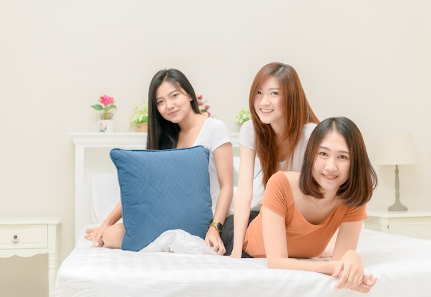 Portrait of three pretty girls smile on bed