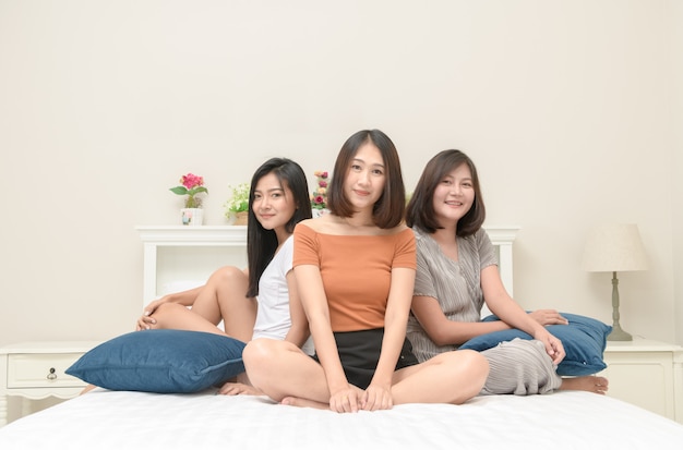 Portrait of three pretty girls smile on bed