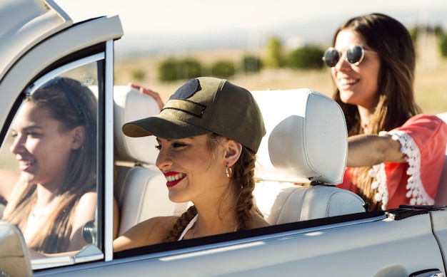 Portrait of three pretty young women driving on road trip on beautiful summer day.