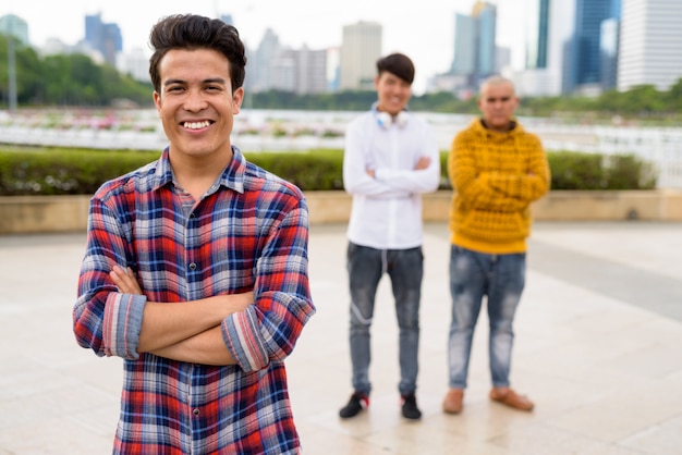 Portrait of three young Asian men together relaxing at the park in Bangkok, Thailand