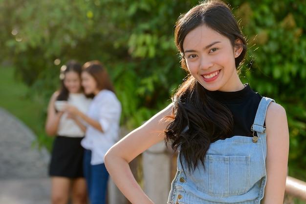 Portrait of three young Asian women as friends together relaxing at the park outdoors