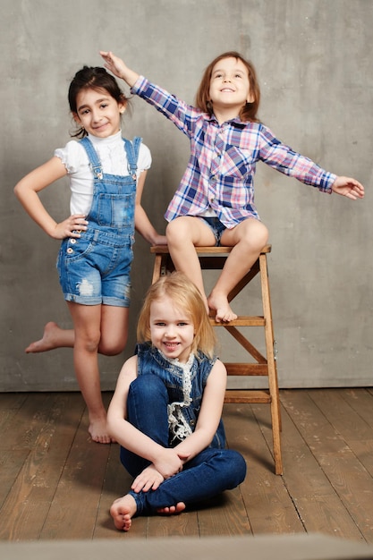 Portrait of three young girls girlfriends on the background of a concrete wall