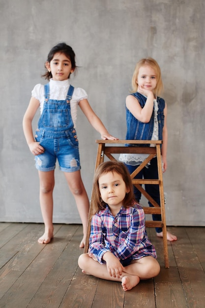 Portrait of three young girls girlfriends on the background of a concrete wall