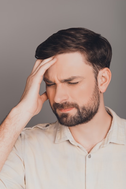 Portrait of tired depressed young man with strong headache