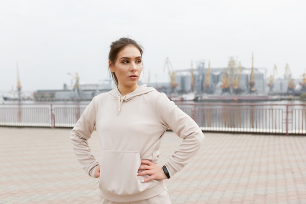 Portrait of a tired fit woman runner on the background of an industrial city