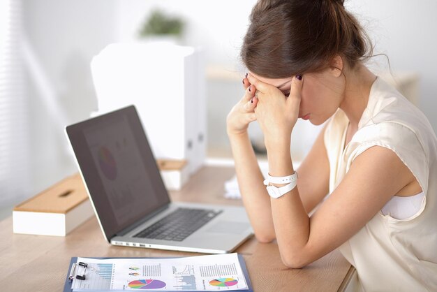 Portrait of tired young business woman with laptop computer at the office