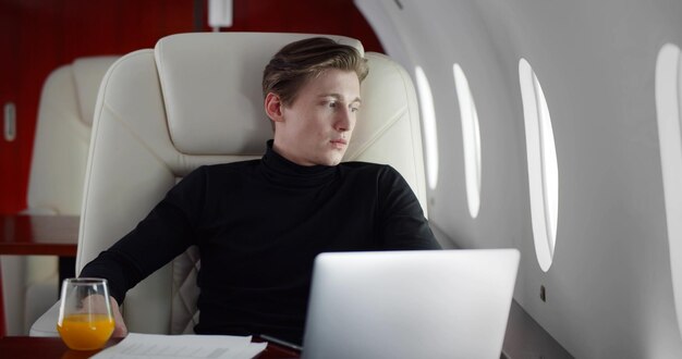 Portrait of tired young businessman flying first class