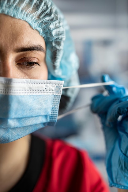 Portrait of tired young doctor taking off medical face mask after a shift in clinic Healthcare concept