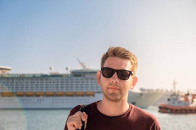 Portrait of tourist man in sunglasses standing in front of big cruise ship in port of bar montenegro