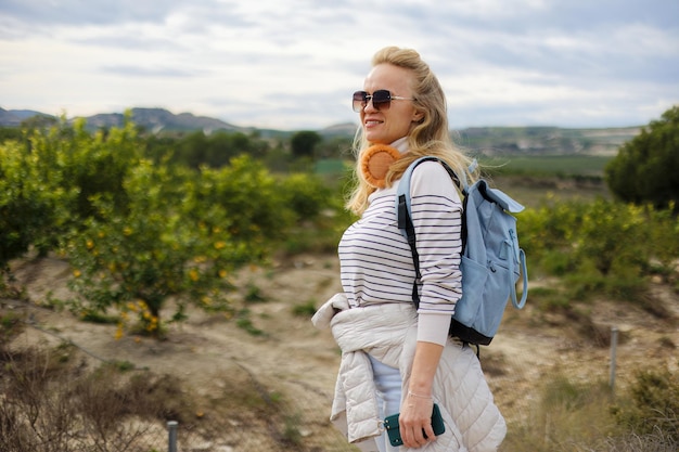 Portrait of a tourist woman against the background of a garden of orange trees