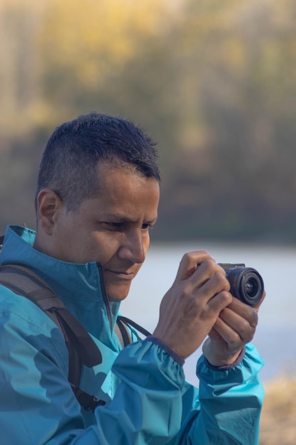 Photo portrait of traveler man at lake in autumn taking a photo with the digital camera