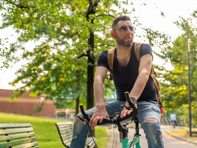 Photo portrait of a trendy young cyclist riding a minimalist bike in an urban green setting from home to work through the park an ecological and sustainable city transport concept