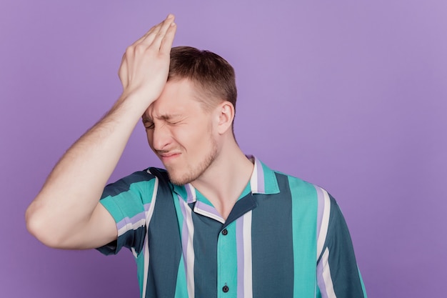 Portrait of troubled stupid guy palm head make mistake failed on purple background