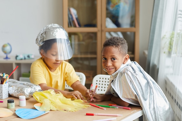 Ritratto di due ragazzi afro-americani che fanno tute spaziali mentre si gode lezione di arte e artigianato in età prescolare o centro di sviluppo