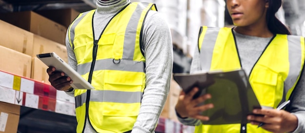 Photo portrait two african american engineer team shipping order detail on tablet check goods and supplies on shelves with goods inventory in factory warehouselogistic industry and business export