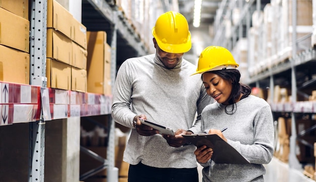 Photo portrait two african american engineer team shipping order detail on tablet check goods and supplies on shelves with goods inventory in factory warehouselogistic industry and business export