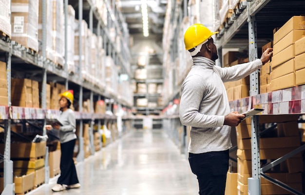 Photo portrait two african american engineer team shipping order detail on tablet check goods and supplies on shelves with goods inventory in factory warehouselogistic industry and business export