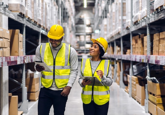 Photo portrait two african american engineer team shipping order detail on tablet check goods and supplies on shelves with goods inventory in factory warehouselogistic industry and business export