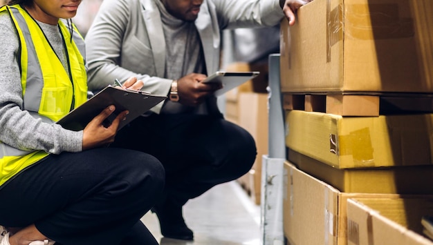 Портрет двух афро-американских инженеров команды детали заказа на доставку на планшете проверяют товары и принадлежности на полках с запасами товаров на складе фабрикилогистическая промышленность и экспорт бизнеса