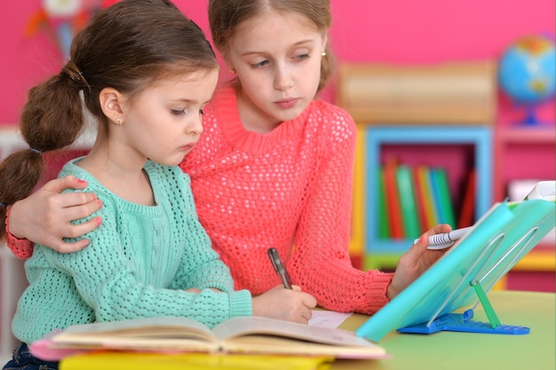 Portrait of two beautiful little girls doping homework