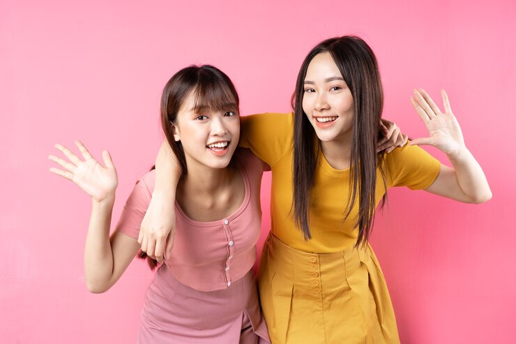 Photo ピンクの壁にポーズをとって2人の美しい若いアジアの女の子の肖像画