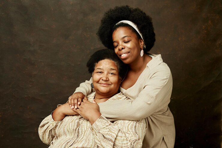 Photo portrait of two black women embracing on brown background