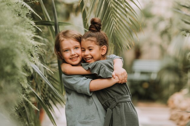 Portrait of two charming smiling girls belonging to different races surrounded by tropical leaves