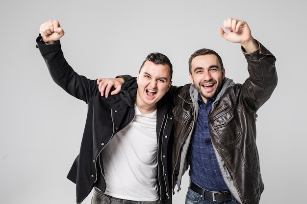 Portrait of a two cheerful young men celebrating isolated over white background