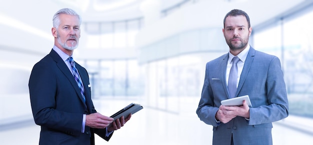 Портрет двух коллег-бизнесменов, использующих планшет перед современной ИТ-компанией