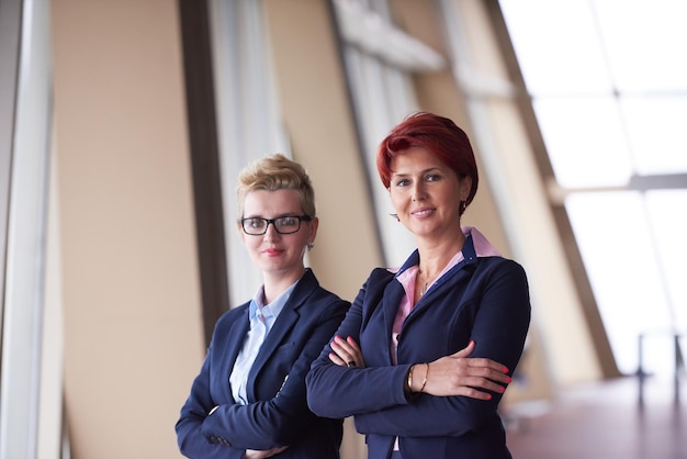 portrait  of two corporate business woman at modern bright office interior standing in group as team