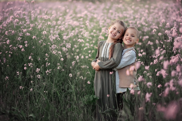 Portrait of two cute happy children. Twins boy and girl in summer. On a pink flowering field.