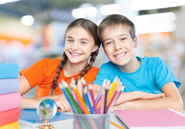 Portrait of two diligent girls looking at camera at workplace with schoolboys on background